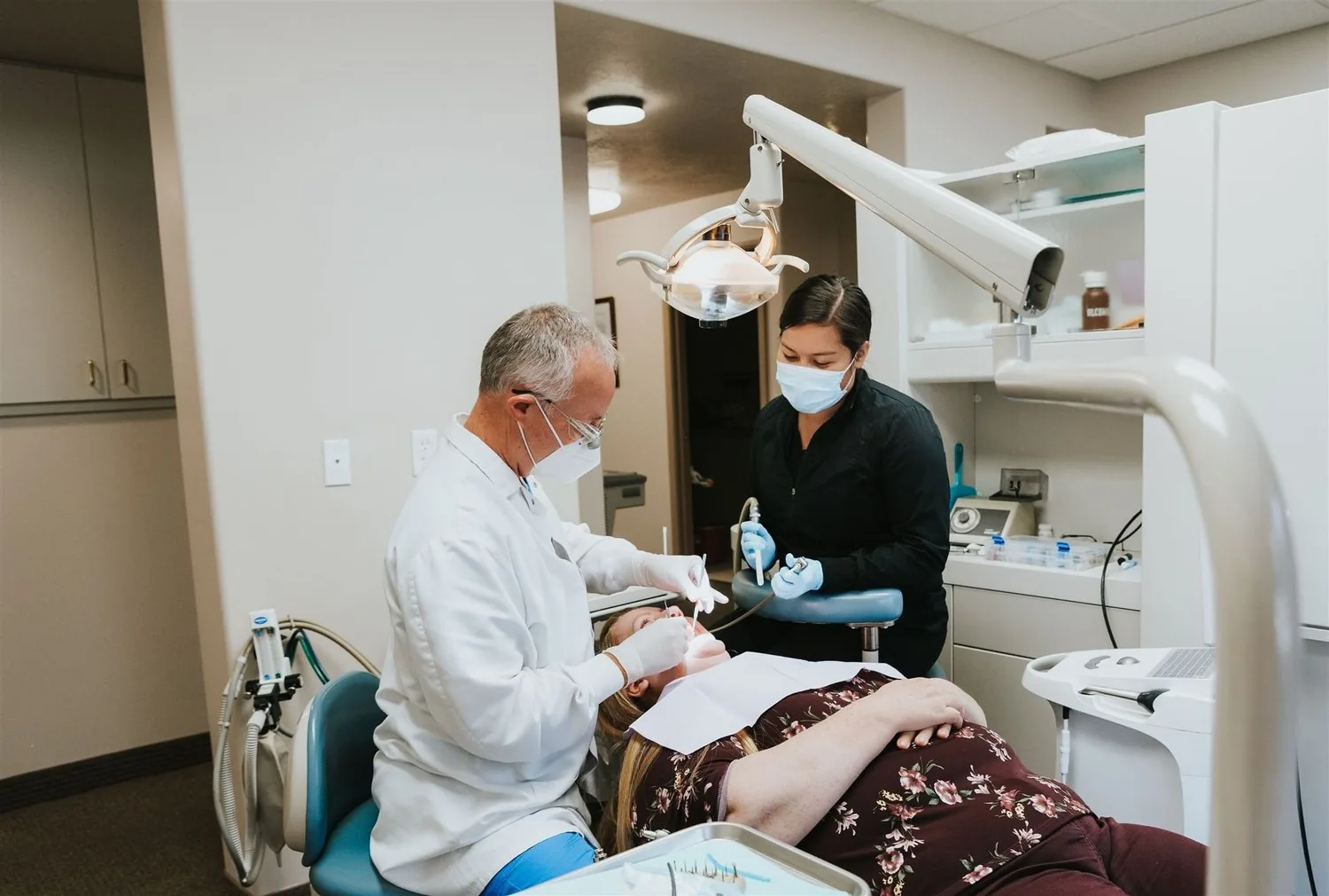 A dentist and assistant treating a patient lying in a dental chair.